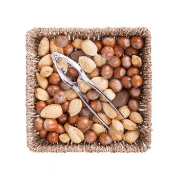 Mixed nuts in a woven basket with nut cracker, isolated on white