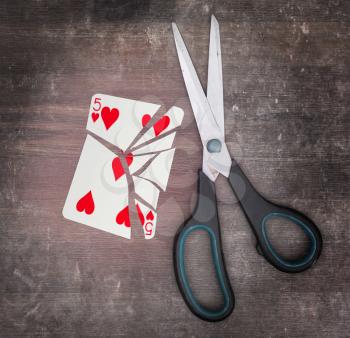 Concept of addiction, card with scissors, five of hearts