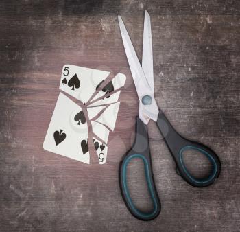Concept of addiction, card with scissors, five of spades