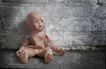 Abandoned doll sitting on a concrete floor