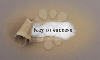 Text appearing behind torn brown envelop - Key to success