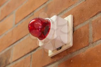 Red emergency light on a brick wall, selective focus