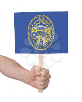 Hand holding small card, isolated on white - Flag of Nebraska