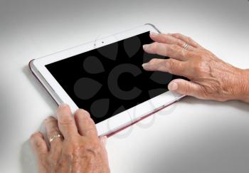 Hands of senior lady relaxing and reading the screen of her tablet, black screen visible
