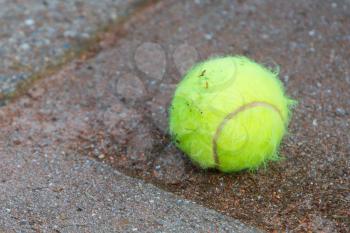 Single tennis ball isolated on a stone floor