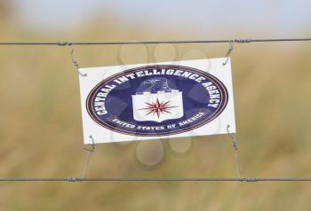 Border fence - Old plastic sign with a flag - CIA