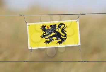 Border fence - Old plastic sign with a flag - Flanders