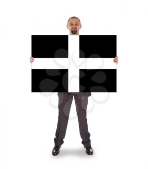 Smiling businessman holding a big card, flag of Cornwall, isolated on white