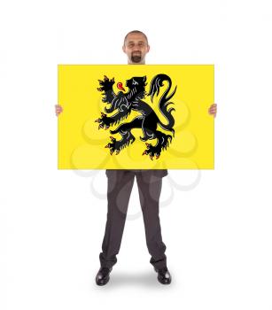 Smiling businessman holding a big card, flag of Flander, isolated on white