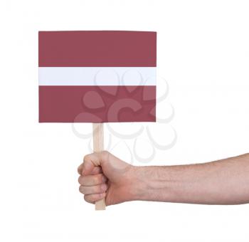 Hand holding small card, isolated on white - Flag of Latvia