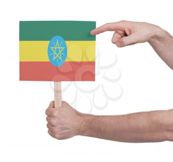 Hand holding small card, isolated on white - Flag of Ethiopia