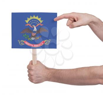 Hand holding small card, isolated on white - Flag of North Dakota