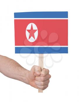 Hand holding small card, isolated on white - Flag of North Korea