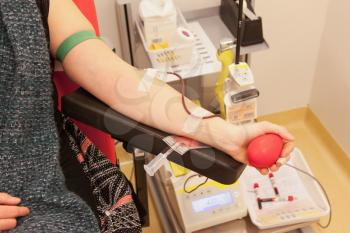 Donor in an armchair donates blood at hemotransfusion station, selective focus