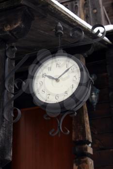 nice ancient clock hanging near the wooden building