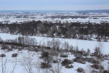 winter field, frozen white river and forest on the background