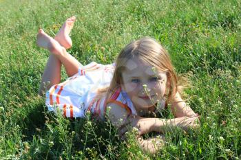 little fashionable girl lying on the green grass