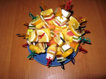 Multi-coloured dessert from fruit candy and a lemon with swords