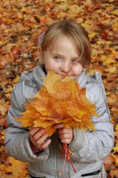 sympathetic little girl plays with leaves in the park