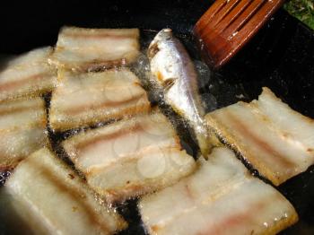 The image of tasty fried bacon on a frying pan