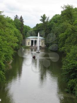 Picturesque pond with a fountain and pergola in park
