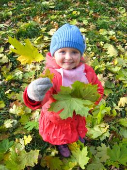 The little girl with yellow leaf in the park in autumn