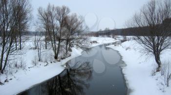 Winter landscape with snow-covered banks and river and trees