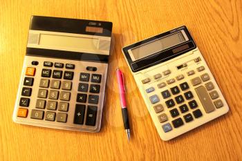 The image of pair of calculators on a table and the pen
