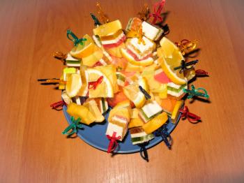 Multi-coloured dessert from fruit candy and a lemon with swords