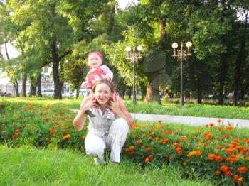 Happy mother and the daughter having a rest in park with flowers