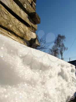Layer of a snow besides peasant's log hut in the spring
