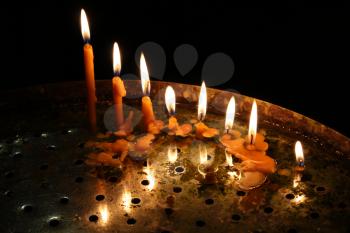 image of row bright burning church candles on candlesticks