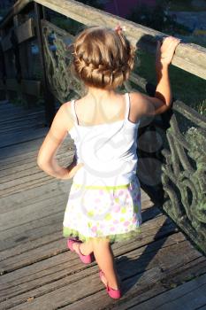 the little girl with nice hair-do standing beside railing
