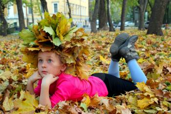 little girl lying on the yellow leaves in the park