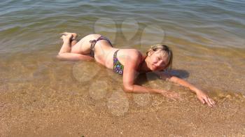 sympathetic girl lays on sand at the sea