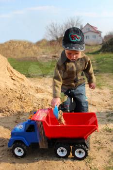image of little boy plays with toy lorry on the sand