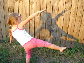 Shadow of playing girl on the wooden fence