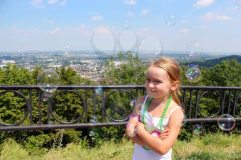 little girl swelling soap big bubbles out of city