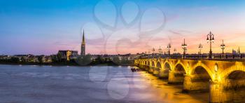 Panorama of Pont de pierre, old stony bridge in Bordeaux in a beautiful summer night, France