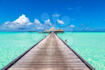 MALDIVES - JUNE 24, 2018: Water Villas (Bungalows) and wooden bridge at Tropical beach in the Maldives at summer evening