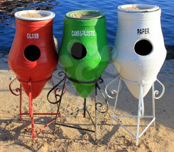 Three Colorful Recycle Trashcans on a Beach 
