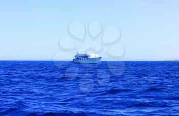 Sea Blue Water Background at Sun Light. White Ship floats on Water.