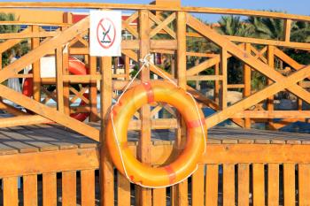 Orange lifebuoy handing on a wooden bridge