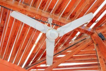 Old vintage white ceiling fan attached on wooden roof planks