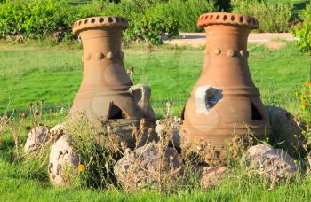 Old vintage vases and stones on tropical green grass background