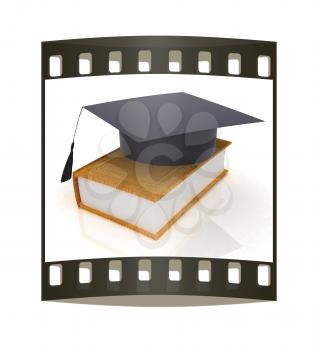 Graduation hat on a leather book on a white background. The film strip
