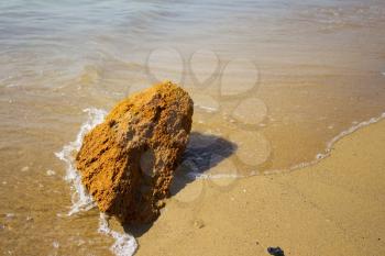 Lone yellow stone on the sea shore