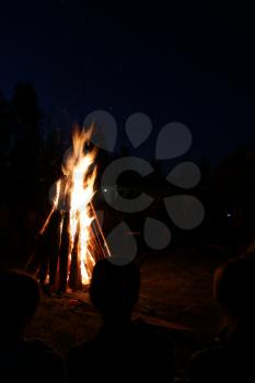 People sit at night round a bright bonfire