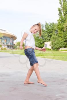 Cute girl with blond hair jumping on one leg