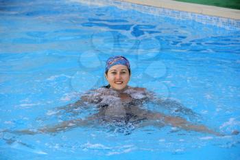 Beautiful young smiling girl sailling in pool in blue kerchief